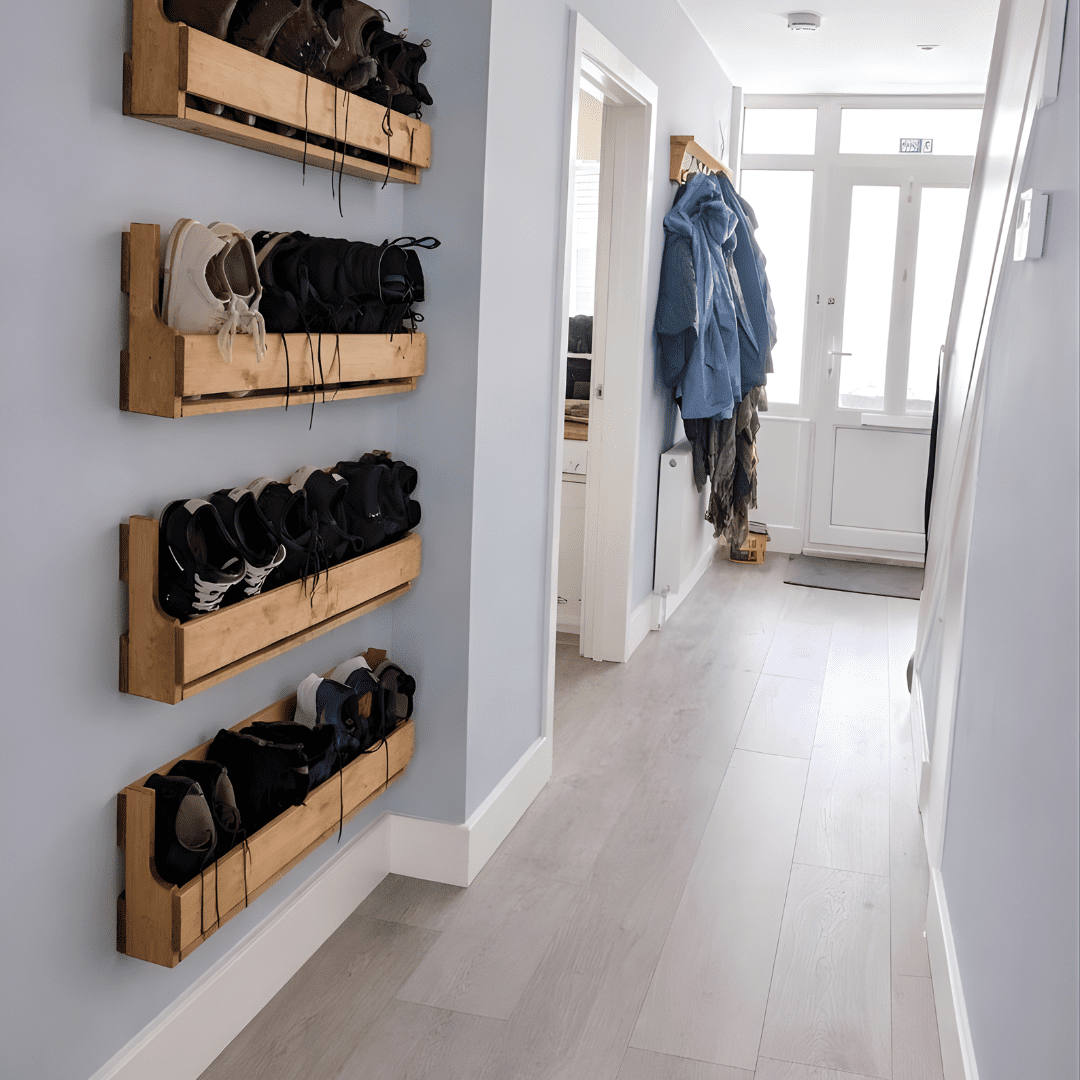 Four wooden wall mounted shoe racks installed vertically in long hallway.